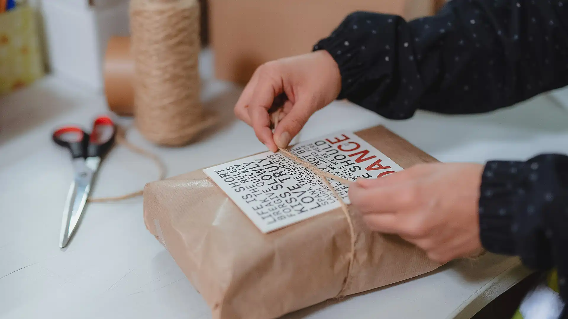 Hände verpacken ein Paket mit Schleife